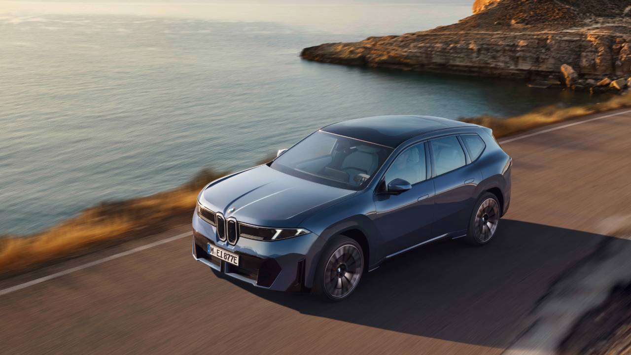 En grå BMW iX3 sett skrått forfra i solnedgang